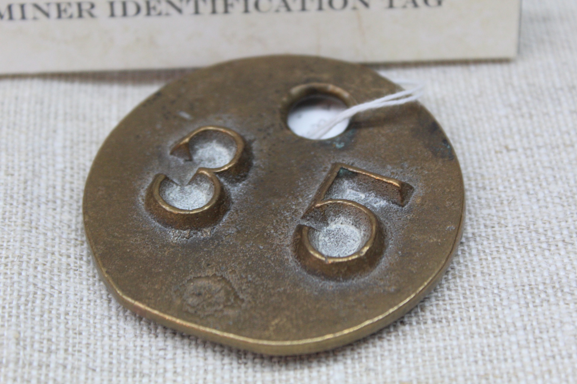 A miner identification tag with 35 embossed on it.